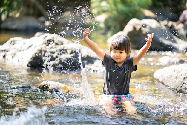 Niña asiática jugando en la secuencia de cascada con salpicaduras de agua