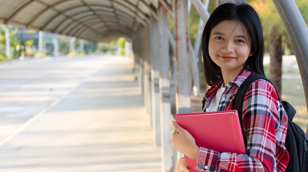 Foto niña asiática con libro y mochila en la escuela