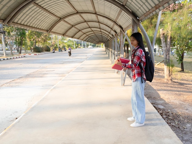 Foto niña asiática con libro y mochila en la escuela