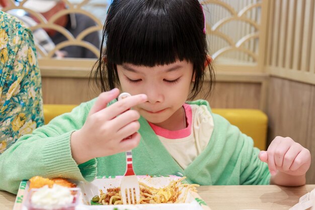 Una niña asiática linda comiendo comida