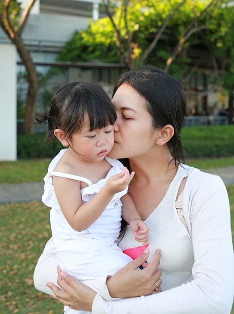 Niña asiática en madre abrazo en el parque