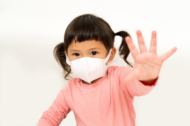 Niña asiática con máscara para proteger pm2.5 y mostrar parada de mano