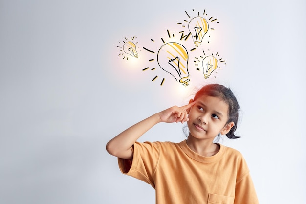 Foto niña asiática mirando hacia arriba con íconos de bombillas sobre la creatividad en el concepto de fondo gris idea del futuro