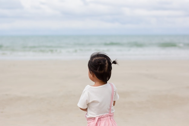 Niña asiática mirando el mar