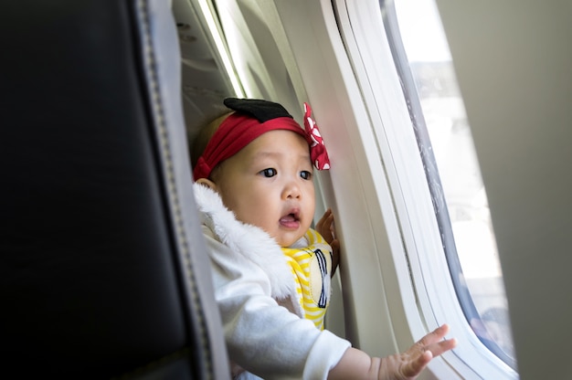 Foto niña asiática mirando por la ventana en avión