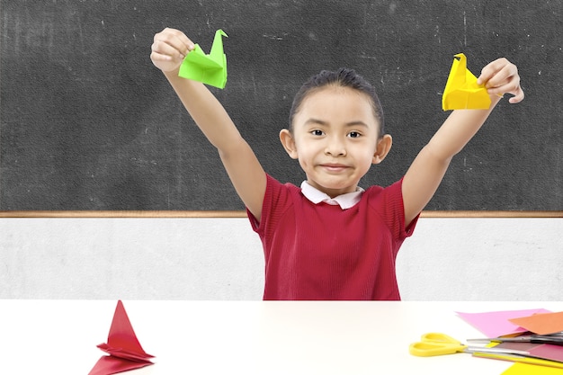 Niña asiática mostrando su papel de gallina en el aula