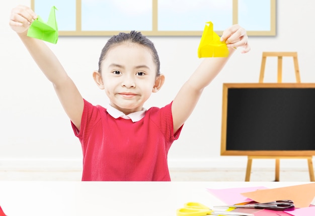 Niña asiática mostrando su papel de ganso en el aula