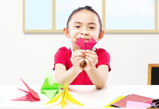 Niña asiática mostrando su papercraft en el aula