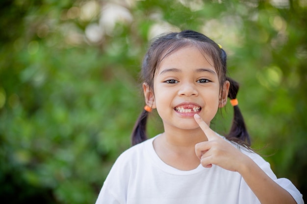 Niña asiática muestra un diente que falta