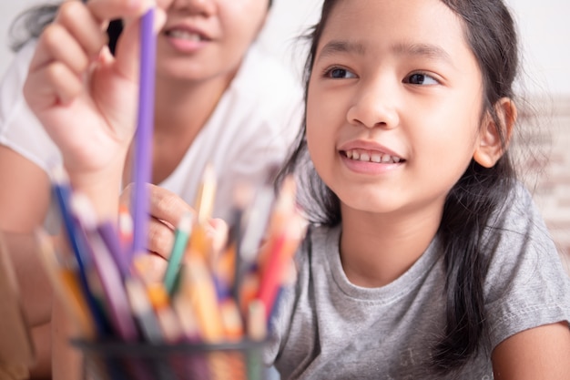 Niña asiática y una mujer seleccionando un color para pintar