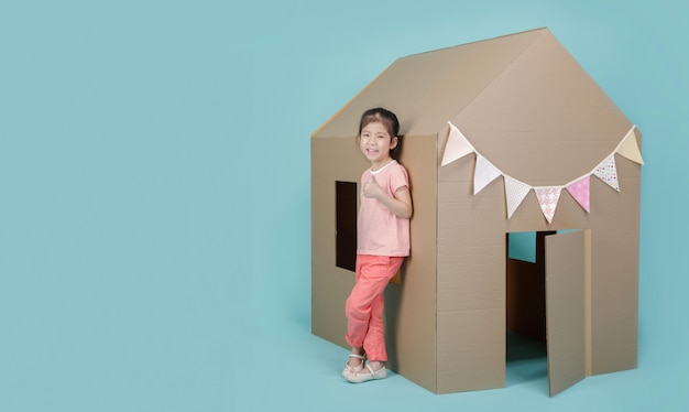 Niña asiática niño jugando con casa de cartón