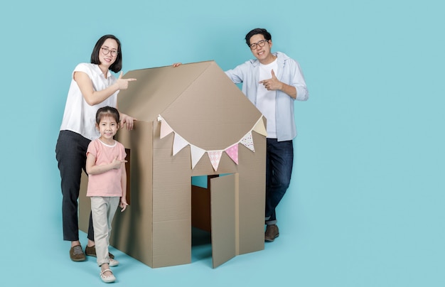 Niña asiática niño con madre y padre con su casa de cartón aislado en azul banner largo con espacio de copia para su texto, nuevo hogar con concepto de familia