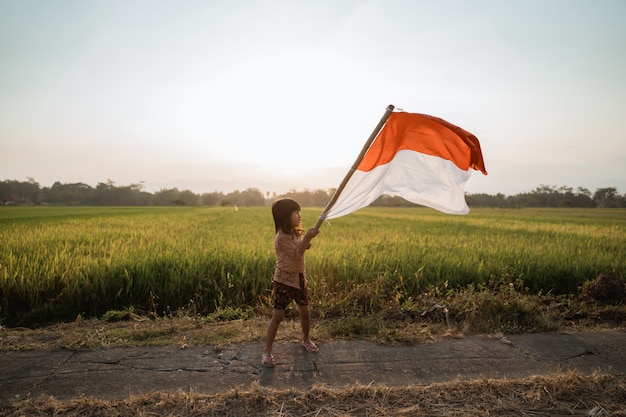 Niña asiática ondeando la bandera de Indonesia