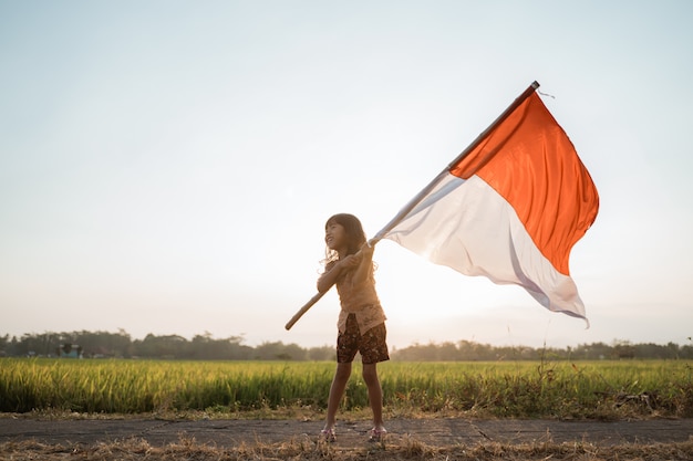 Niña asiática ondeando la bandera de Indonesia