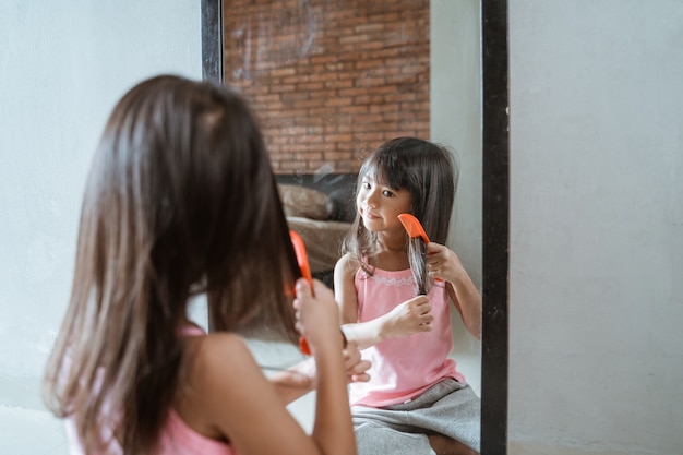 Foto niña asiática peinándose