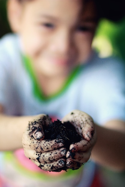 Niña asiática plantando, sosteniendo el suelo en la mano. Feliz de aprender de la naturaleza
