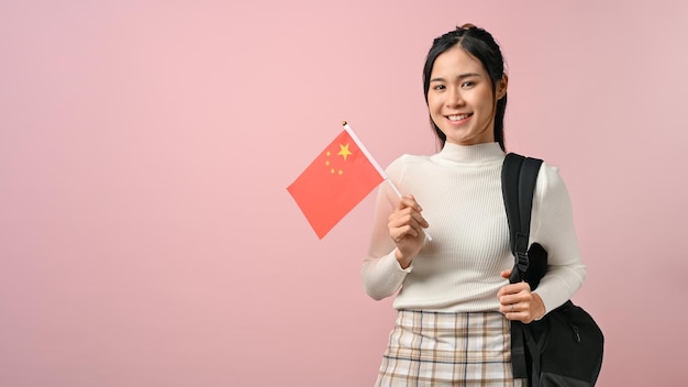 Niña asiática que muestra una bandera de China en el concepto de educación de fondo rosa aislado