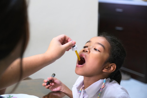 Niña asiática que tiene gotas de medicina