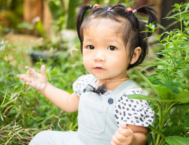 Niña asiática sentada en el parque verde