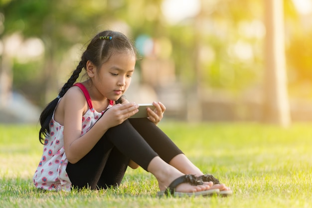 Niña asiática con smartphone en un jardín