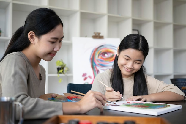 Niña asiática sonriente pintando sobre lienzo durante la clase de arte