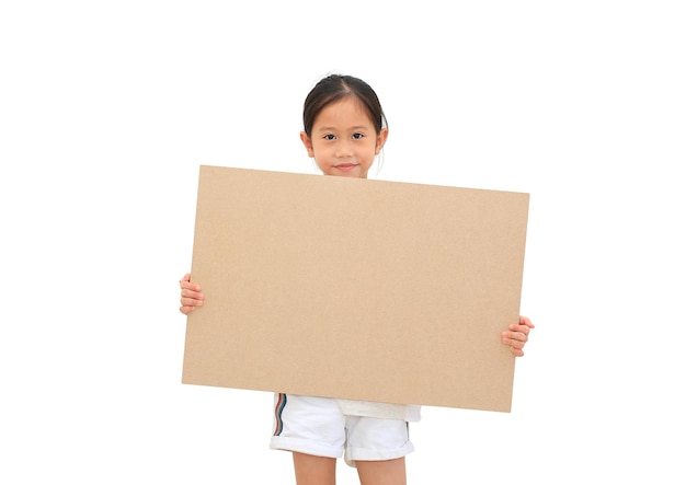 Niña asiática sosteniendo un gran tablero marrón vacío para una pancarta de medios aislada en un fondo blanco con espacio para copiar