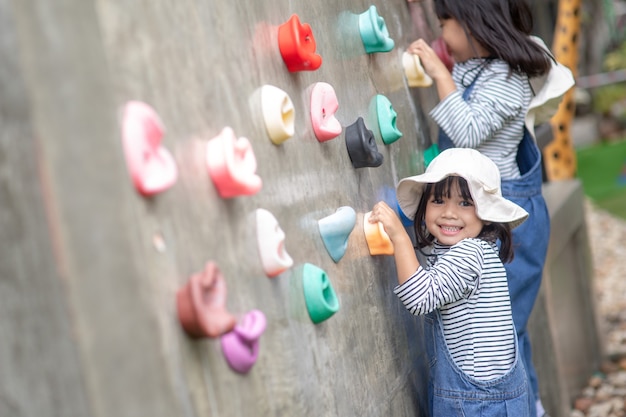 Niña asiática subiendo una pared de roca