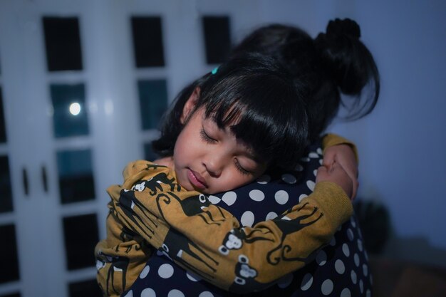 Foto niña asiática con sueño está durmiendo en el brazo de su madre.