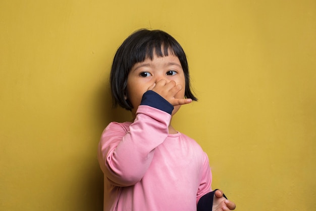 Niña asiática tapándose la nariz debido a un mal olor