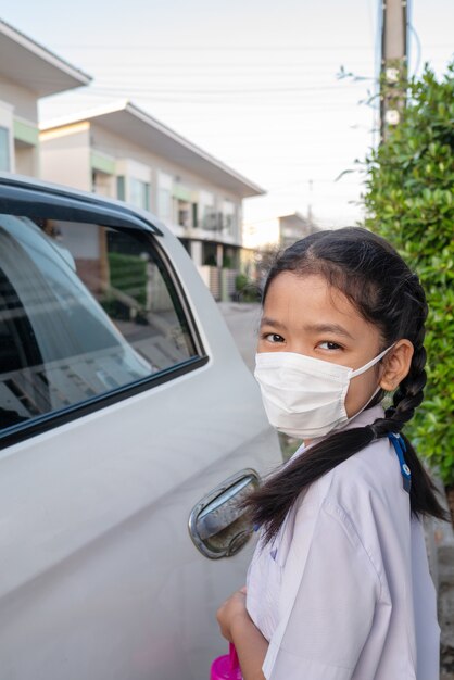 Una niña asiática en uniforme con máscara protectora