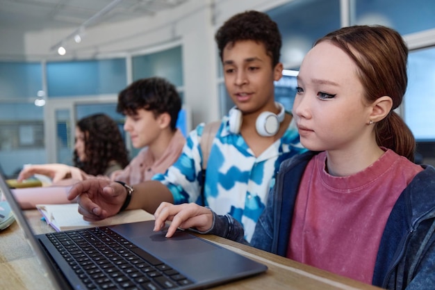 Niña asiática usando computadora durante la clase de tecnología en la escuela
