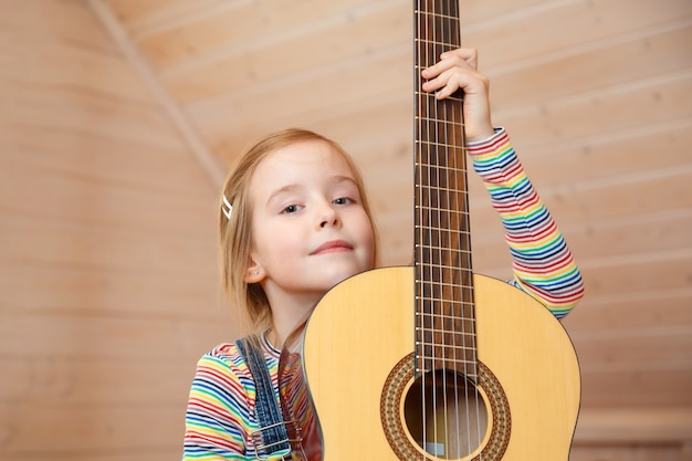 niña asoma detrás de una funda de guitarra en casa.