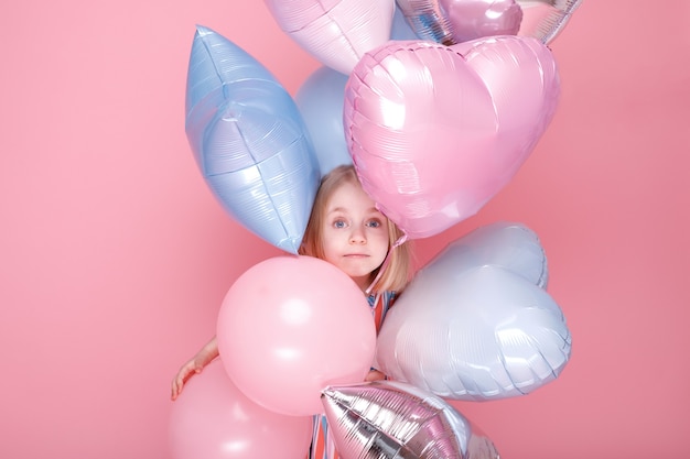 Una niña asoma detrás de los globos. Día del Niño