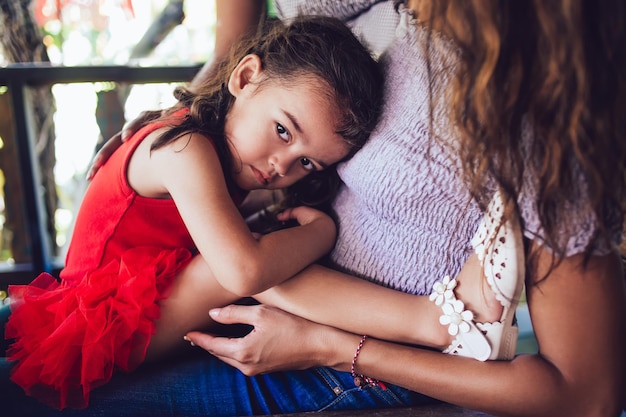 Niña asustada sentada aferrada a la madre