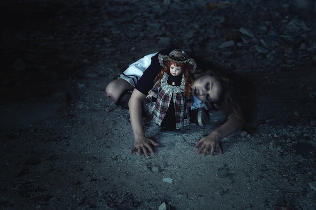 Una niña asustadiza con una muñeca en el suelo en una casa abandonada.una idea para halloween