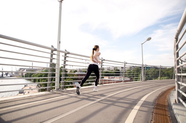 Una niña atleta corre en una caminadora a través del puente.