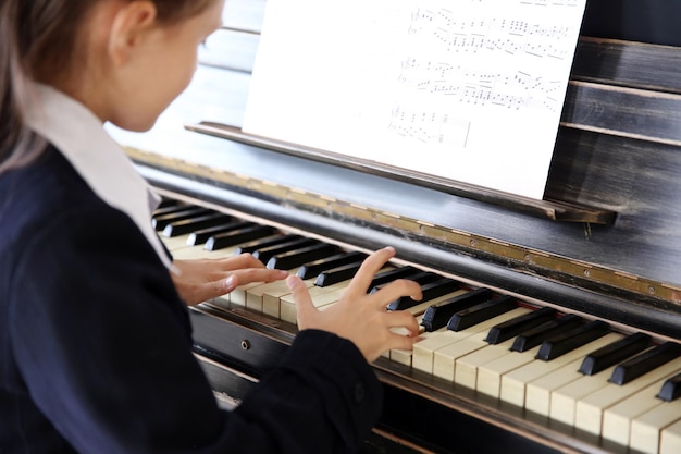 Niña atractiva toca el piano