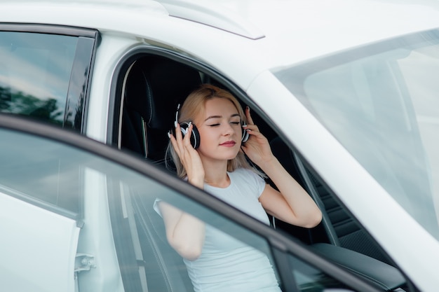 Niña con auriculares escuchando música al lado del coche