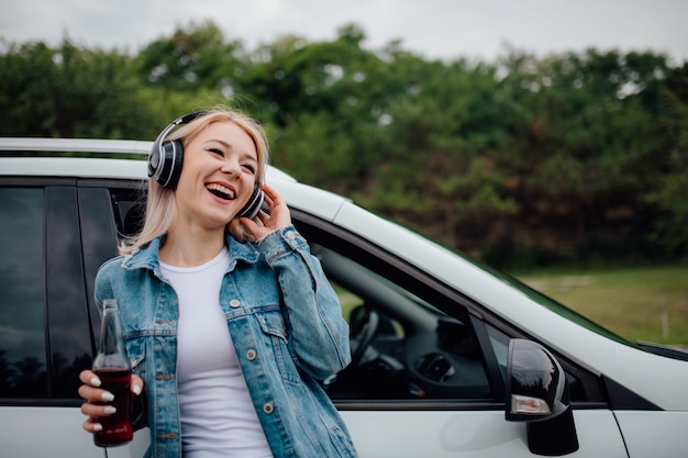 Niña con auriculares escuchando música al lado del coche