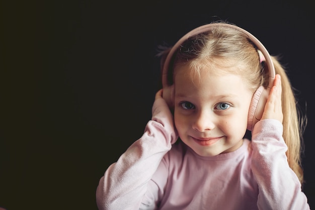 Niña en auriculares escuchando música, retrato de un niño caucásico