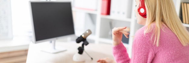 Una niña con auriculares de pie en una mesa en la oficina.