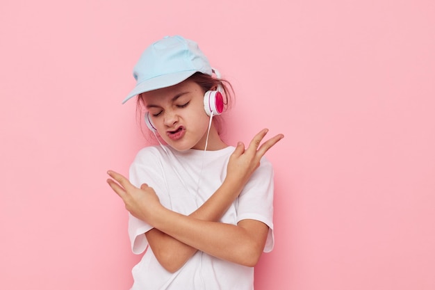 Niña en auriculares posando sobre un fondo rosa