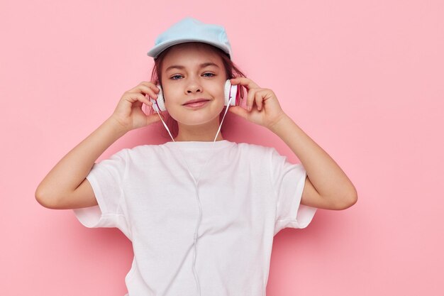 Niña en auriculares posando sobre un fondo rosa