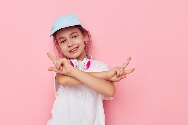 Niña en auriculares posando sobre un fondo rosa