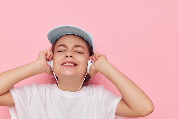 Niña en auriculares posando sobre un fondo rosa