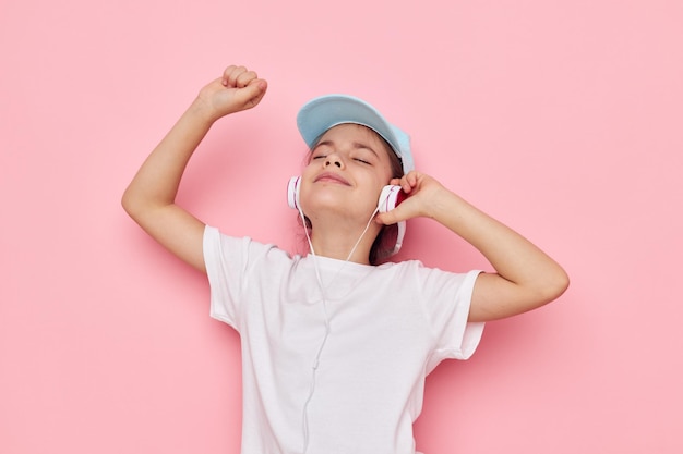 Niña en auriculares posando sobre un fondo rosa