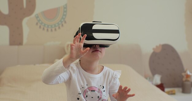 Foto niña con auriculares de realidad virtual interactuando con el mundo digital curiosa