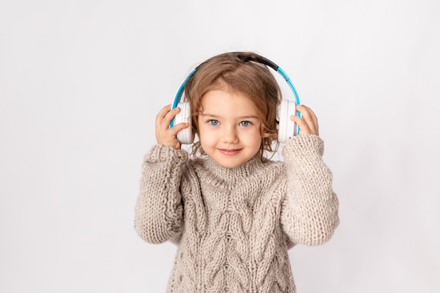 Niña con auriculares sobre un fondo blanco escuchando música