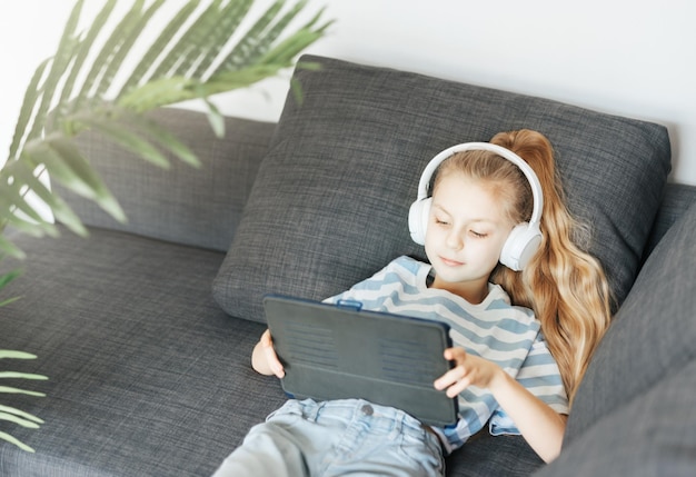 Niña con auriculares y tablet en casa