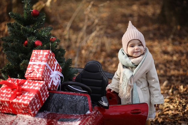 niña en un auto con regalos y un árbol de navidad